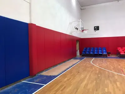 Угол баскетбольного зала ЦСКА с синими и красными протекторами, кольцом и зрительскими креслами