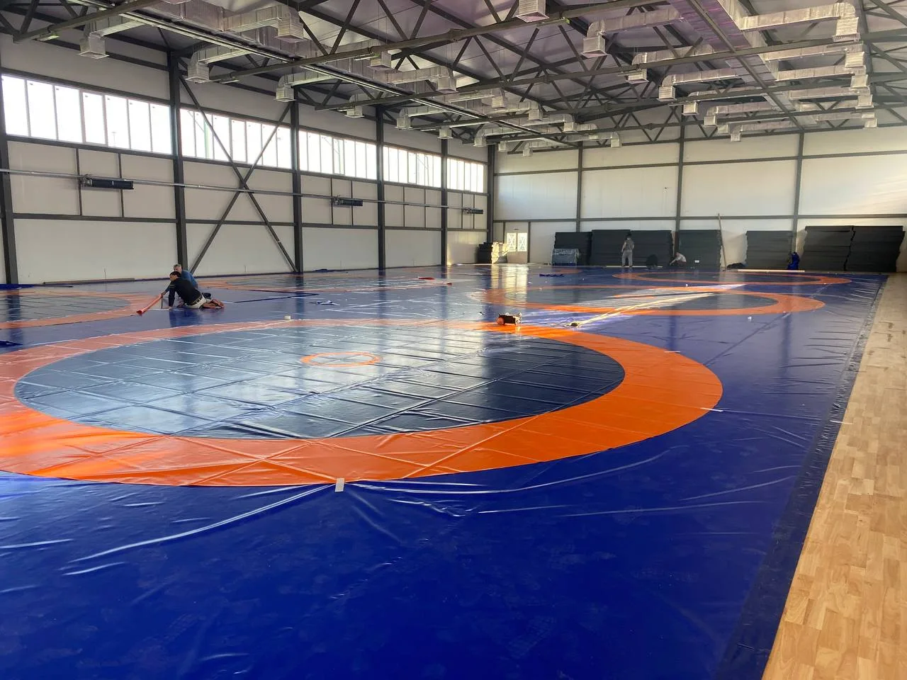 Процесс установки и укрепления борцовского ковра на полу зала стадиона Анжи-Арена