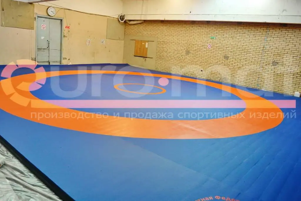 Борцовский ковёр синий с оранжевой зоной в зале борьбы с кирпичными стенами
