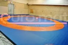 Борцовский ковёр синий с оранжевой зоной в зале борьбы с кирпичными стенами