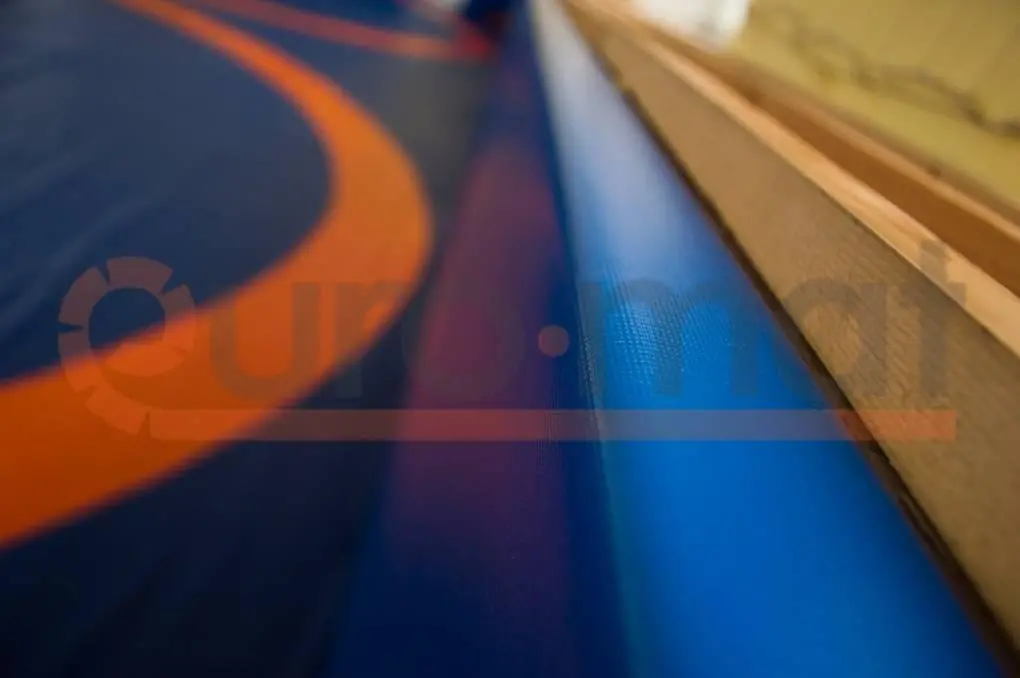 Борцовский ковёр крупным планом — синий край с оранжевой разметкой у деревянного бортика