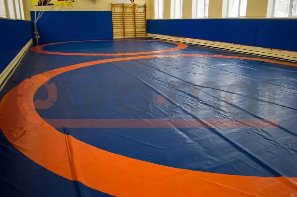Сине-оранжевый борцовский ковёр и синие стеновые протекторы в школьном зале борьбы