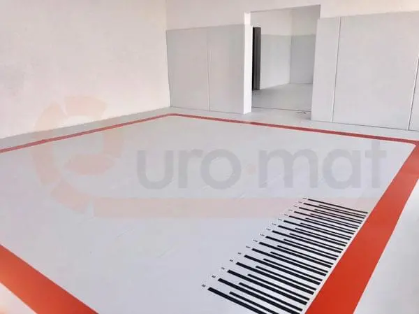 Борцовский ковёр белого цвета с красной разметкой и шкалой прыжков в зале борьбы в Анапе со стеновыми протекторами