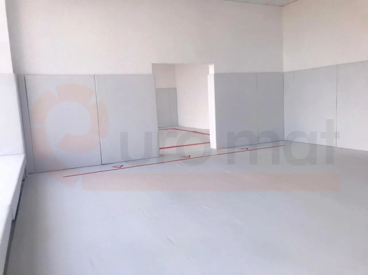 Белый борцовский ковёр с красной разметкой и серые стеновые протекторы в борцовском зале Анапы