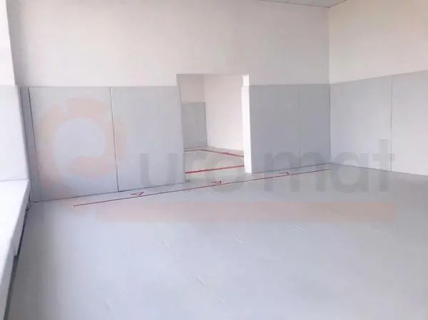 Белый борцовский ковёр с красной разметкой и серые стеновые протекторы в борцовском зале Анапы