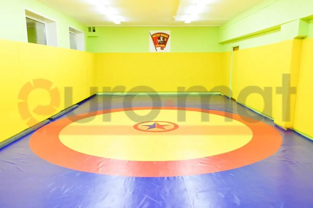 Борцовский ковёр сине-красно-жёлтый с жёлтыми стеновыми протекторами в зале борьбы