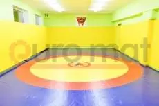 Борцовский ковёр сине-красно-жёлтый с жёлтыми стеновыми протекторами в зале борьбы