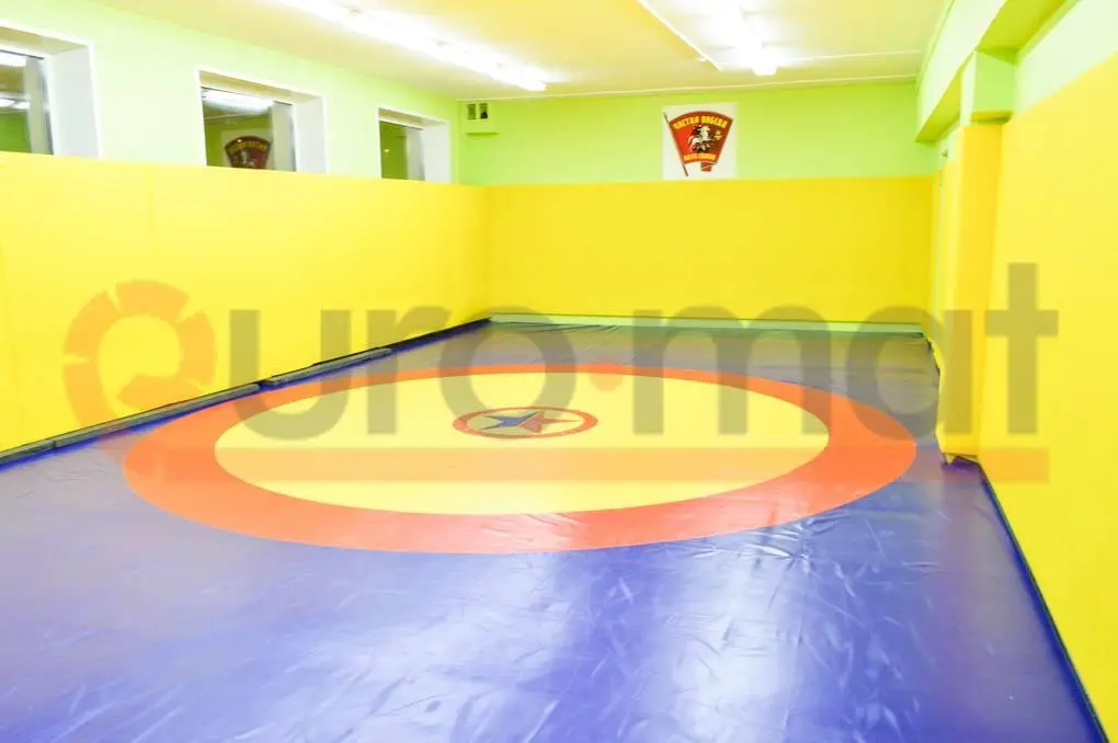 Борцовский ковёр в зале борьбы, жёлтые стеновые протекторы по периметру