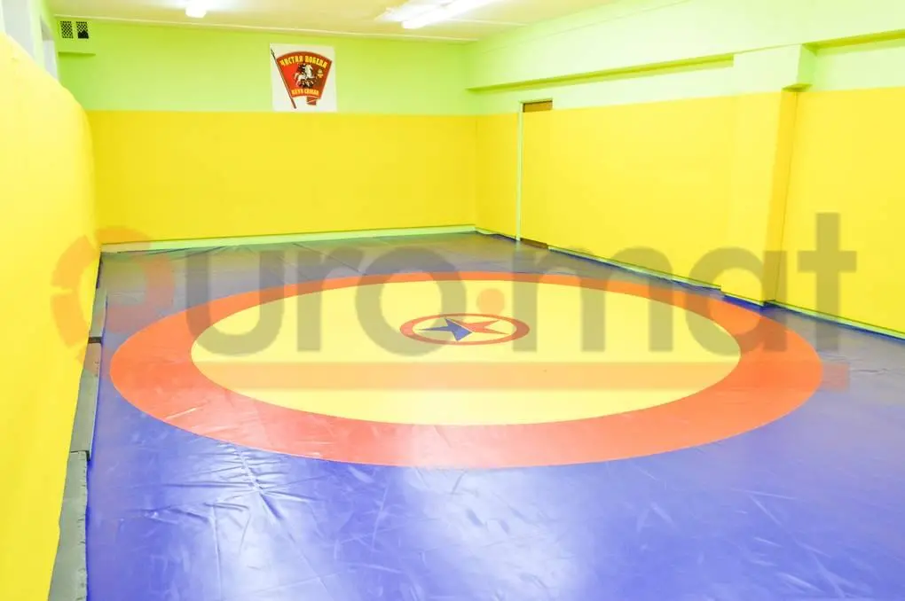 Борцовский ковёр с круговой разметкой и жёлтые протекторы стен в зале единоборств