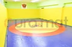 Борцовский ковёр с круговой разметкой и жёлтые протекторы стен в зале единоборств