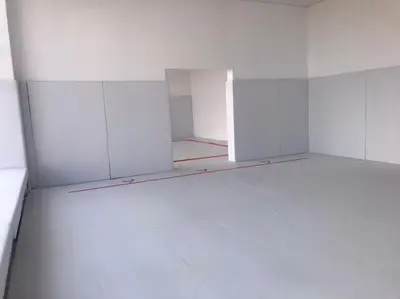 Белый борцовский ковёр с разметкой и стеновые протекторы, вид через проём второго зала