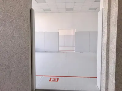 Вид из коридора через проём на второй зал с белым ковром, цифра 2 на полу, протекторы