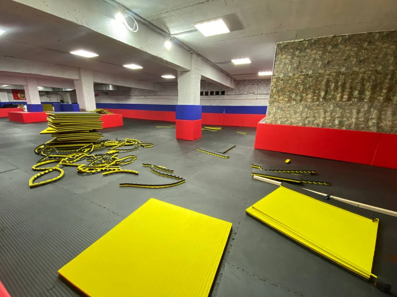 Процесс укладки чёрных будо-матов толщиной 40 мм на подготовленное основание зала