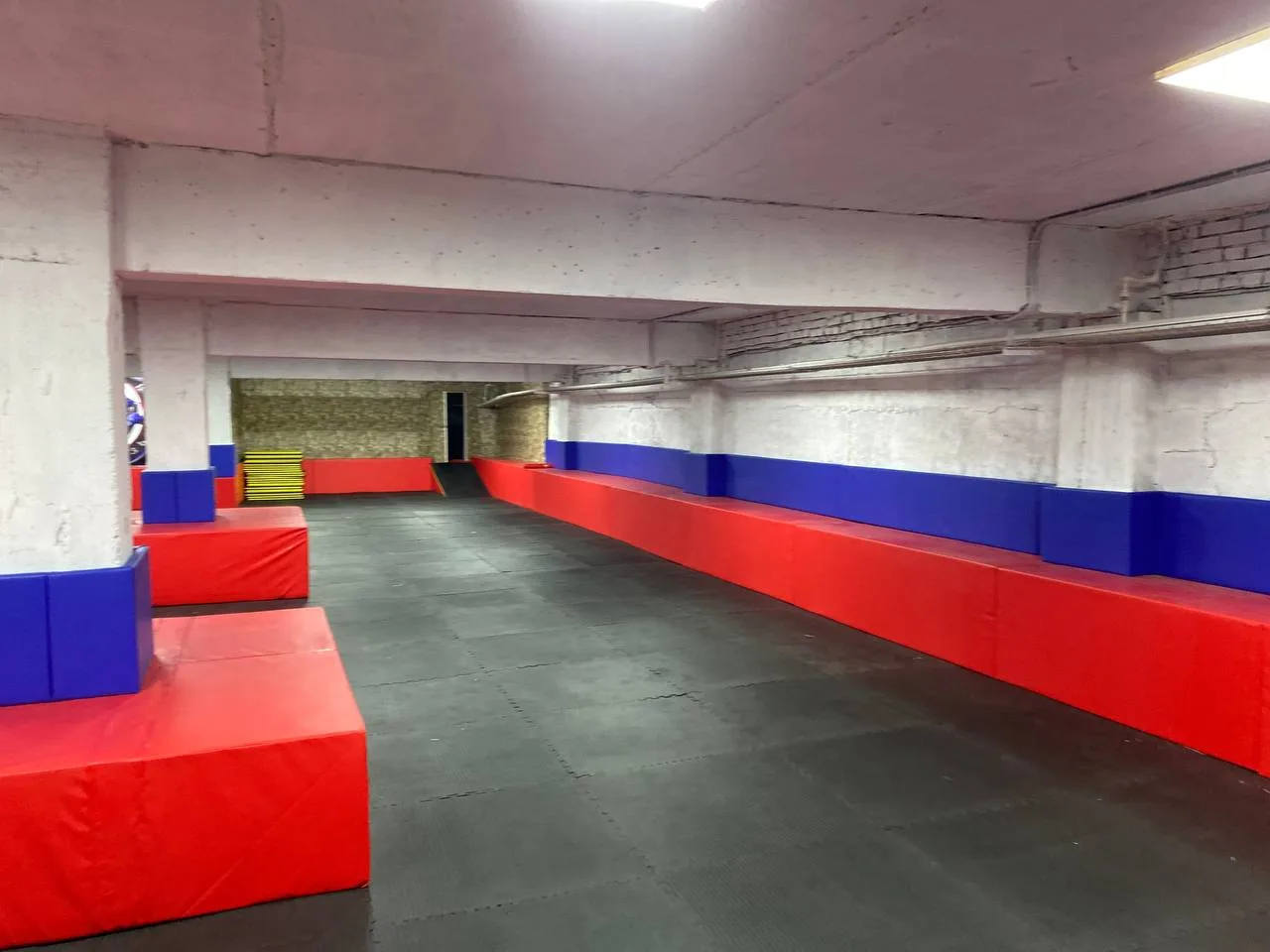 Завершённый монтаж: полная защита одной из стен зала чёрными и синими стеновыми протекторами до высоты 2 м