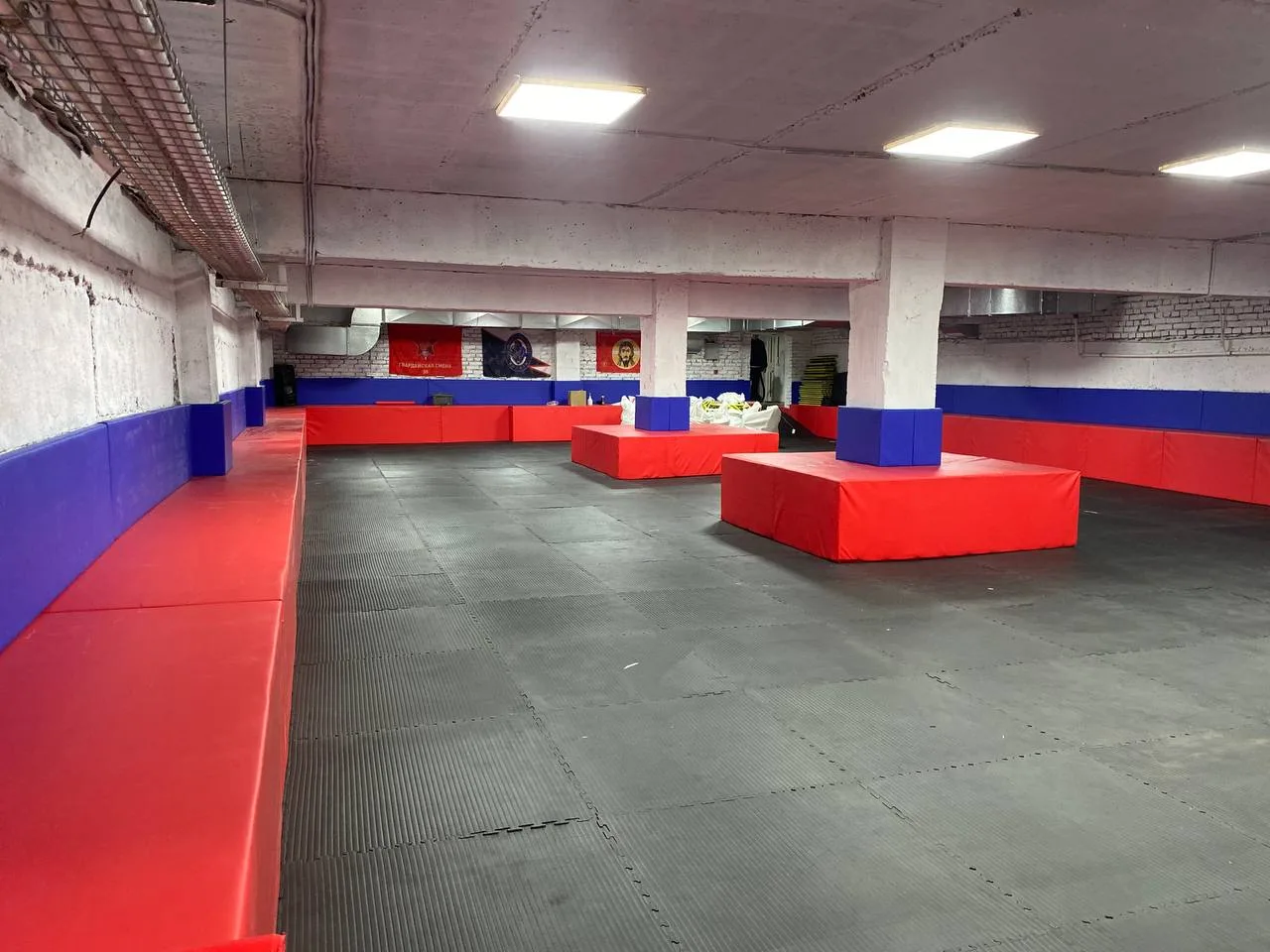 Панорамный вид тренировочного зала: чёрные будо-маты на полу и стеновые протекторы на стенах