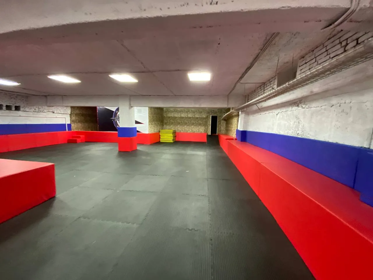 Красные защитные чехлы на колонне зала выделяются на чёрном фоне будо-матов