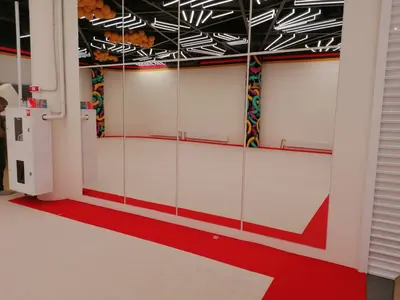 Бежевый гимнастический ковёр с красной окантовкой в зале Gym Family с зеркалами и граффити