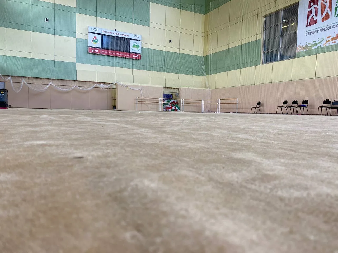 Бежевый ролл-гимнаст в спорткомплексе РЖД с баннерами и табло, вид с пола