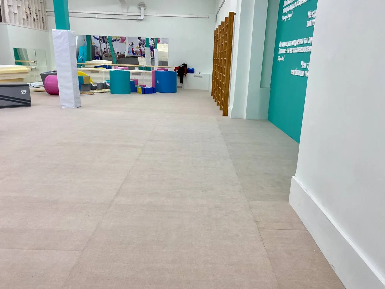 Бежевый ролл-гимнаст в зале гимнастики с бирюзовыми колоннами и зеркалами