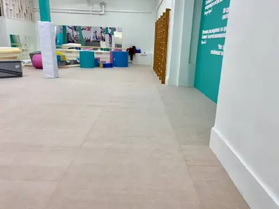 Бежевый ролл-гимнаст в зале гимнастики с бирюзовыми колоннами и зеркалами