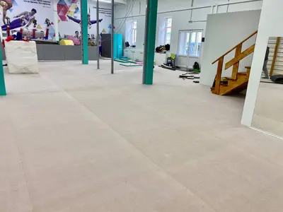 Бежевый ролл-гимнаст в просторном зале с постерами гимнастов и лестницей