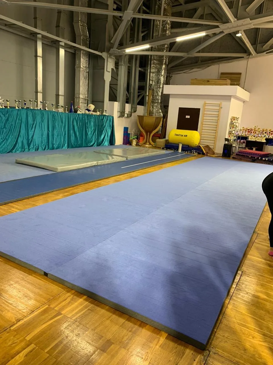 Голубой ковёр для гимнастики из двух дорожек в зале клуба чир спорта с кубками