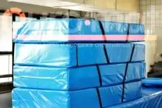 Стопка синих гимнастических матов с чёрными ручками на производстве Евромат