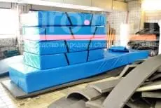 Синие гимнастические маты на производстве среди заготовок из поролона