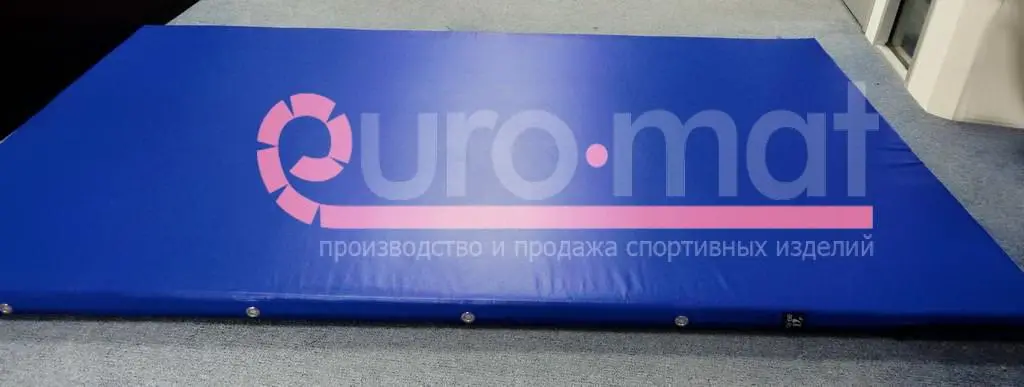 Синий гимнастический мат с люверсами на полу в домашнем спортзале