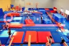 Гимнастический зал с синими и красными матами, бревнами и брусьями