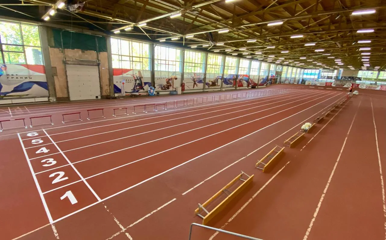 Красная беговая дорожка с разметкой на 6 дорожек в легкоатлетическом манеже Ижевска, барьеры