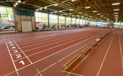 Красная беговая дорожка с разметкой на 6 дорожек в легкоатлетическом манеже Ижевска, барьеры