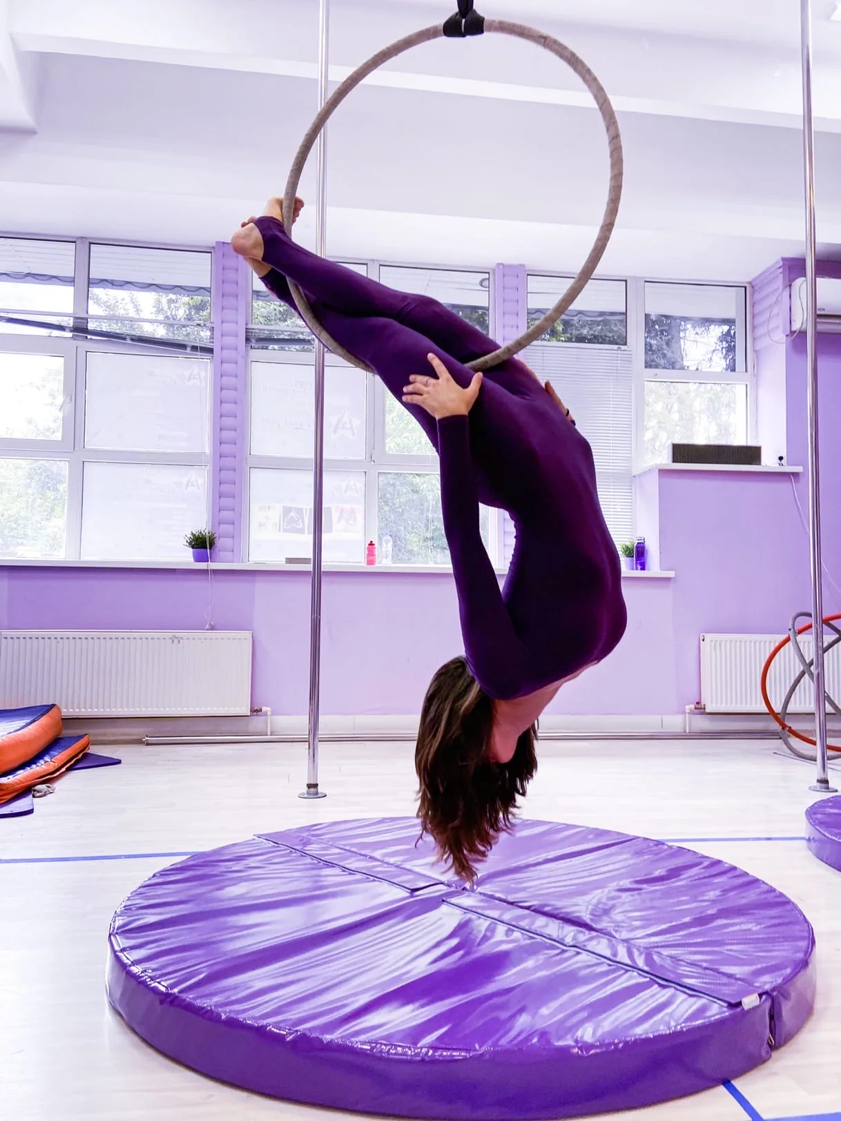 Фиолетовый круглый мат для пилона с гимнасткой на воздушном кольце в студии Астери