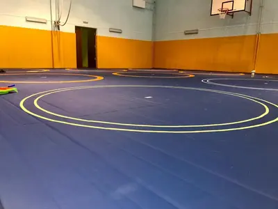 Синий ролл-мат с жёлтыми кругами разметки борьбы вблизи, жёлтые протекторы на стенах