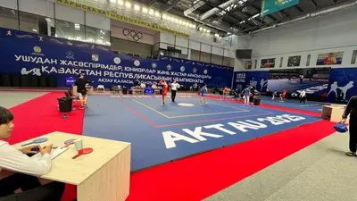 Соревновательная площадка ушу на сине-красном ролл-мате с надписью AKTAU 2025