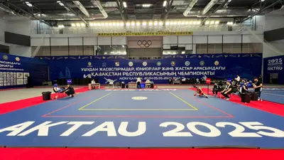 Фронтальный вид на сине-красный ролл-мат с логотипом AKTAU 2025 на турнире ушу