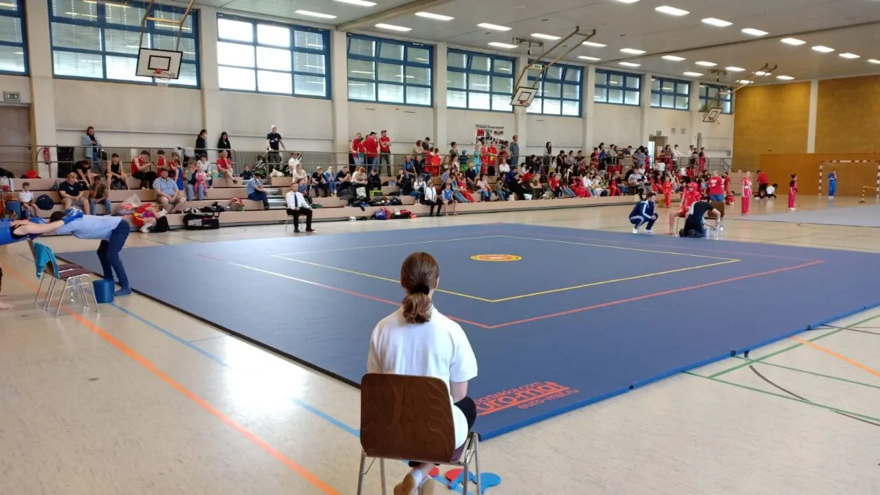 Спортсмены во время тренировки по ушу на синем ролл-мате