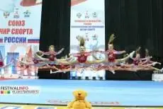 Синие ролл-маты на сцене, девочки в красно-белом выполняют синхронные прыжки