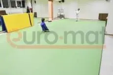 Дети в кимоно тренируются на светло-зелёном ролл-мате в зале единоборств