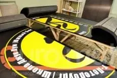 Чёрный ролл-мат с логотипом Джук Лум на деревянных козлах в цеху производства