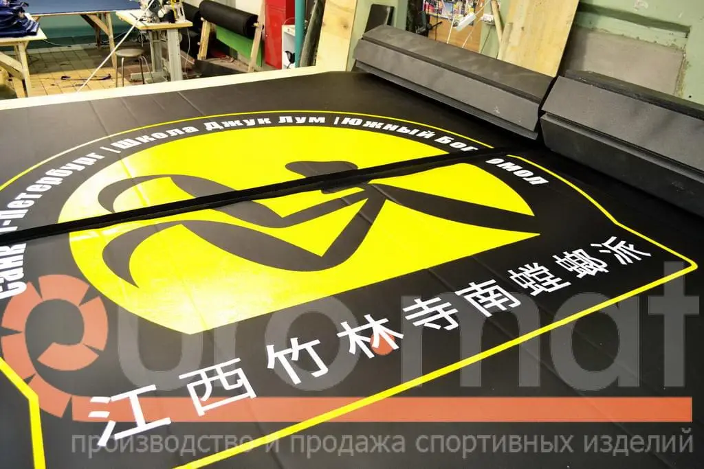 Крупный план логотипа Джук Лум с иероглифами на чёрном ролл-мате в цеху