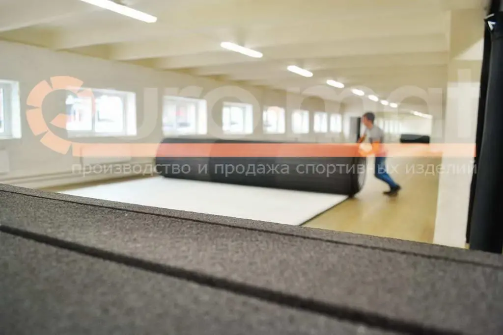 Раскатка чёрного ролл-мата с белым покрытием в бойцовском клубе