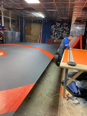 Рабочий шьёт оранжевую окантовку ролл-мата HAMMER FIT на производстве