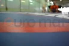 Синий ролл-мат крупным планом с оранжевой разметкой в спортивном зале