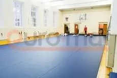 Синие ролл-маты в школьном спортзале с шведскими стенками и баскетбольным щитом