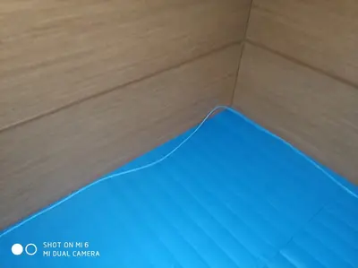 Край синего ролл-мата у деревянной стеновой панели — аккуратный стык покрытия со стеной