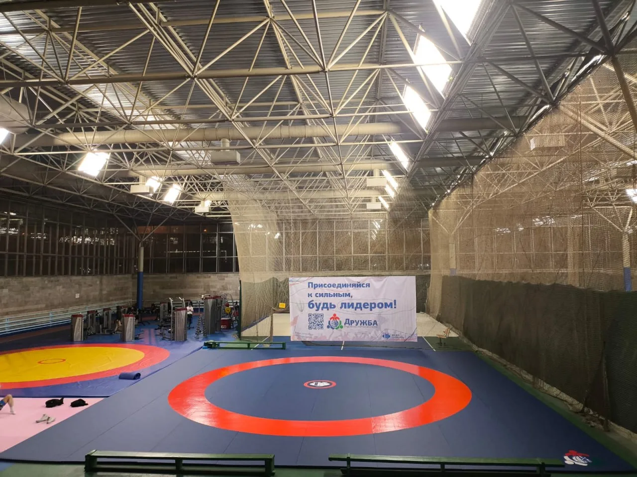 Борцовский зал РУДН с серо-синими ролл-матами, красно-синими кругами и баннером