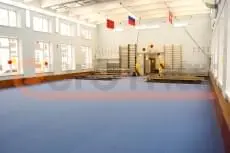 Серо-голубые ролл-маты на полу школьного спортзала с шведскими стенками