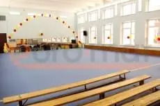 Серо-голубые ролл-маты в школьном спортзале, вид на зеркальную стену и скамейки