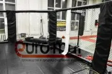 Октагон ММА сбоку с открытыми воротами и чёрным покрытием в клубе Северянин